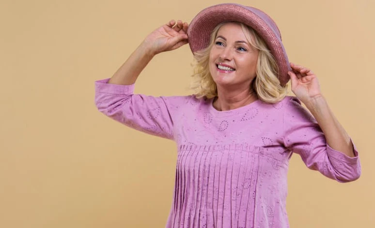 Mujer senior rubia que llevaba un sombrero rosa